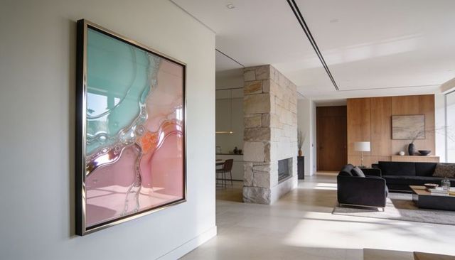 Sunlit minimalist living room featuring framed abstract art, stone fireplace and open plan