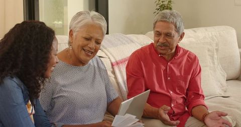 Multigenerational family reviewing finances on tablet in cozy sunlit living room