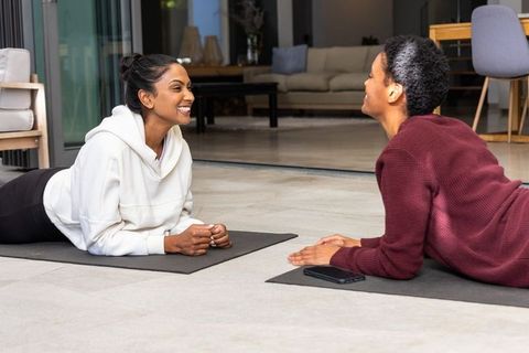 Diverse female friends practicing yoga at home, smiling and chatting during workout