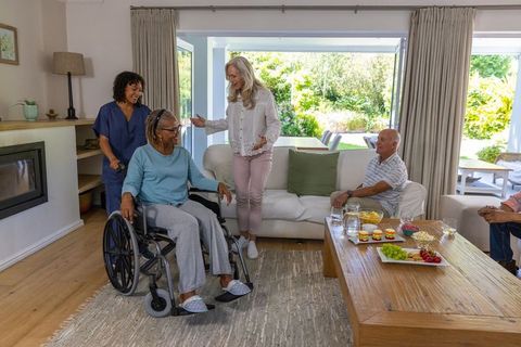 Family gathering in cozy living room with caregiver assisting elderly