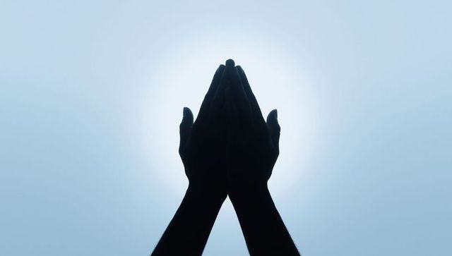 Silhouetted Hands Reaching Upward Against Sunlit Sky