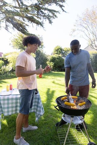 Diverse friends grilling corn in sunny backyard gathering