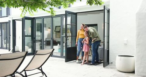 Happy Family Returning Home, Embracing Outdoors Near Modern House