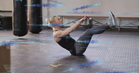 Female athlete holding v-sit on gym mat, balancing core with fitness data overlay