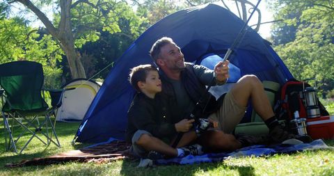 Father and Son Enjoying Camping with Tech Gadgets