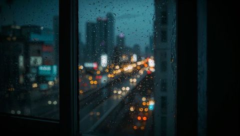 Framing rainy window pane with bokeh city lights at dusk teal amber neon urban traffic