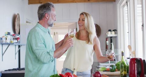 Happy Mature Couple Enjoying Cooking and Wine in Kitchen