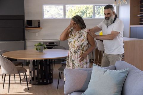 Senior couple sharing tender moment with partner comforting in modern open-plan kitchen