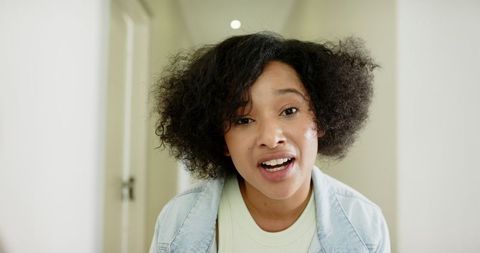 Confident Woman Speaking in Bright Corridor with Denim Jacket