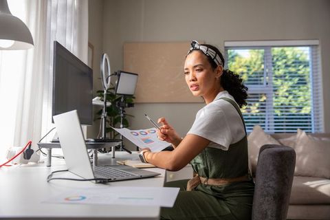 Woman Analyzing Data from Laptop in Contemporary Home Office