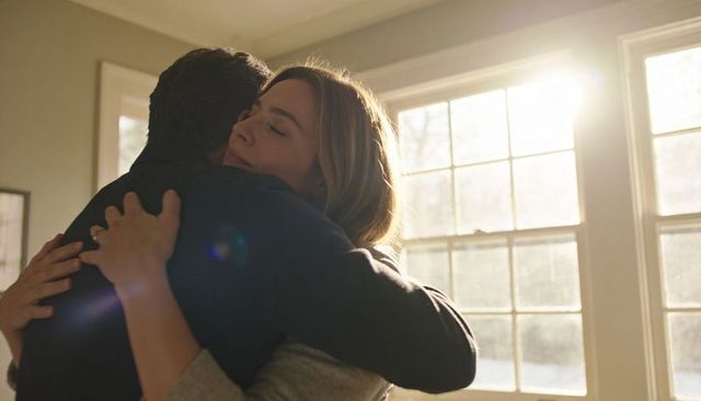 Couple embracing in warm sunlit home interior with window light and lens flare