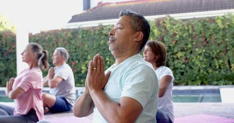 Diverse Group Practicing Yoga Meditation Outdoors by Pool