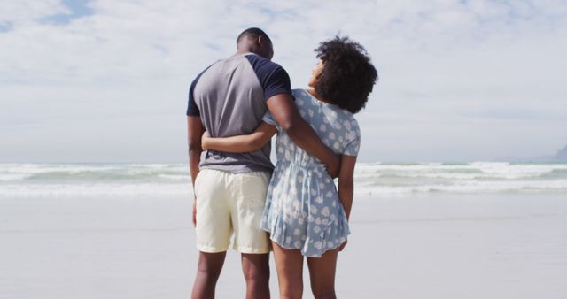 African american couple embracing and smiling at the beach. healthy outdoor leisure time by the sea.