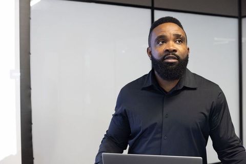 Confident Business Professional Presenting with Laptop and Whiteboard