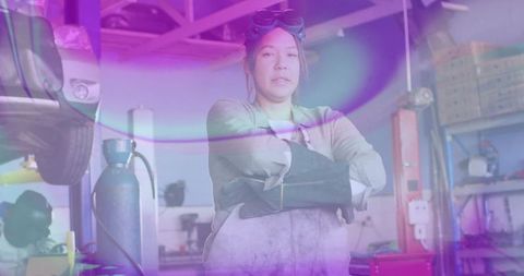 Female mechanic with crossed arms in workshop displaying confidence