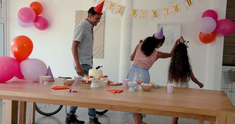 Family celebrates birthday with cake and decorations in festive party hats
