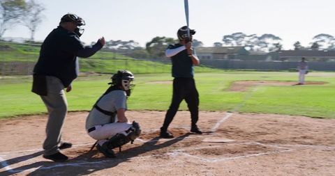 High School Baseball Batter Waiting at Plate with Catcher and Umpire Signaling Play