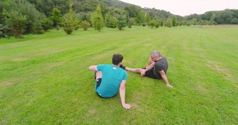 Two Men Resting on Grass After Outdoor Jogging in Park