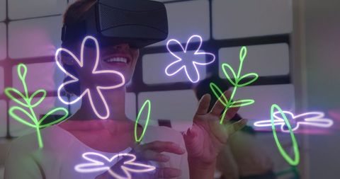 Smiling woman experiencing virtual reality with neon flowers