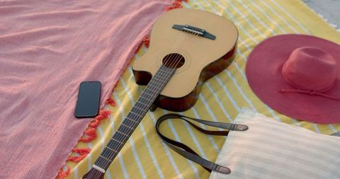 Guitar and beach essentials on blanket for relaxing seaside day