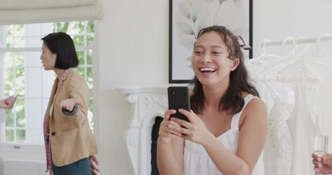 Bride-to-be Trying on Wedding Gown Capturing Joy on Smartphone in Bridal Boutique