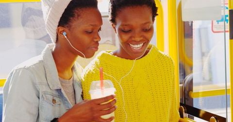 African American Twin Sisters Enjoying Music Together on Bus