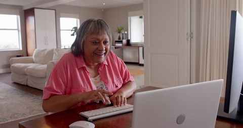 Elderly woman joyful video chatting on laptop in modern home