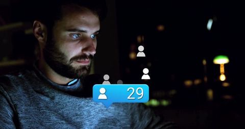 Bearded Man Engaged in Late-Night Digital Connectivity on Laptop