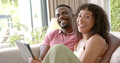 Smiling Couple Relaxing with Tablet on Cozy Sofa