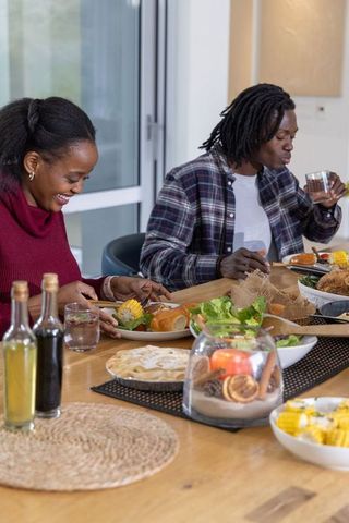 African american couple sharing cozy home dinner with corn, salad and candle centerpiece