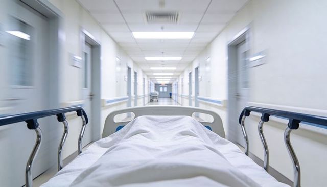 Covered patient on gurney racing down hospital corridor emergency stretcher perspective