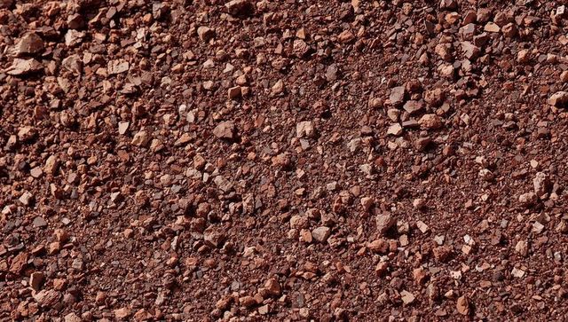 Reddish brown gravel texture covering trail surface with pebbles and dust detail