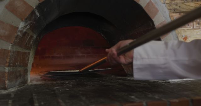 Baker inserting pizza in wood-fired oven using peel - Download Free Stock Images Pikwizard.com