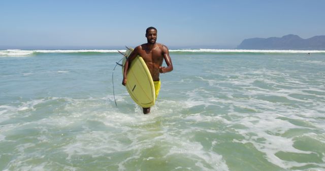 Bare-chested young man walking with surfboard in ocean waves on a sunny day. Perfect for themes related to summer vacations, surfing adventures, beach activities, and active lifestyles.