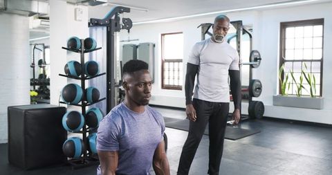 Adult Trainer Supervising Workout Session in Gym