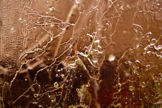 This abstract image features water droplets and streaks on a condensation-covered window, creating intricate textures and patterns. Suitable for backgrounds, creative projects, wall art, and design inspiration. Perfect for illustrating concepts of nature, moisture, and art.