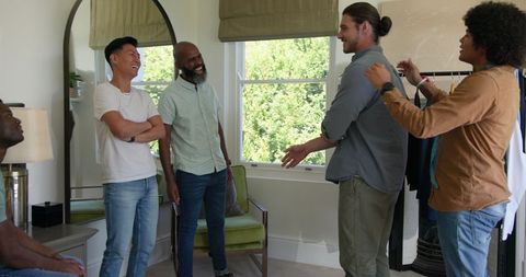 Groom preparing wedding suit with friends in casual home setting
