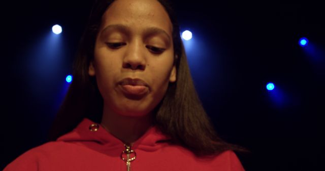 Young Girl In Red Sweater Under Stage Lights With Thoughtful Expression - Download Free Stock Images Pikwizard.com