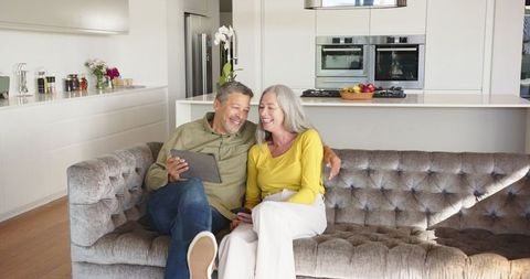 Diverse Senior Couple Relaxing with Tablet in Modern Home Interior