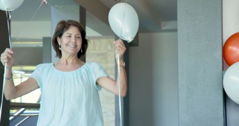 Joyful woman decorating with balloons in modern home