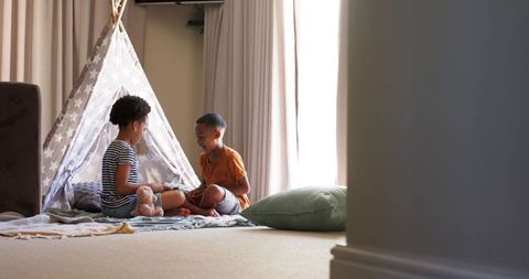 Siblings enjoying playtime in cozy indoor teepee tent