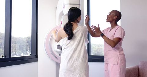 Diverse Woman Undergoing Mammogram While Technician Guiding at Breast Screening Clinic