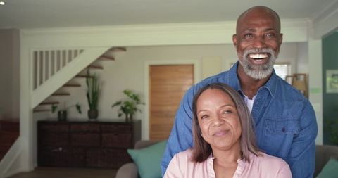 Mature black couple embracing and smiling at home in cozy living room joyful togetherness