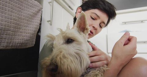 Woman embracing small terrier dog in domestic kitchen scene