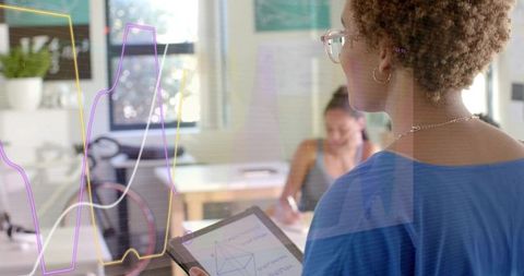 Holding tablet with geometric diagram mentoring student in bright collaborative workspace