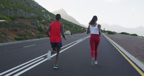 Fit Couple Running on Countryside Road with Mountain View