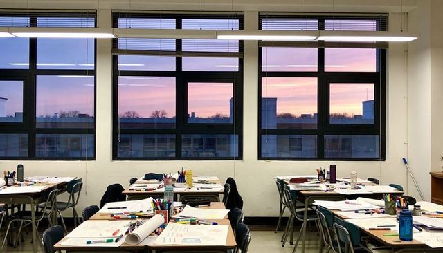 Classroom sunset featuring tables covered in art supplies, markers, water bottles