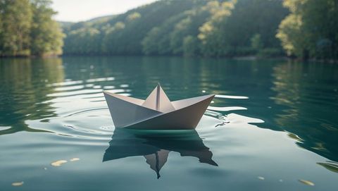Serene origami paper boat on tranquil emerald lake