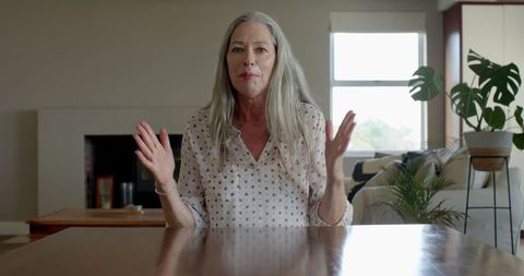 Mature Woman Expressing Surprise While Sitting at Home Table