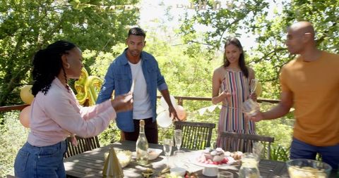 Friends preparing garden table for birthday celebration on sunny day
